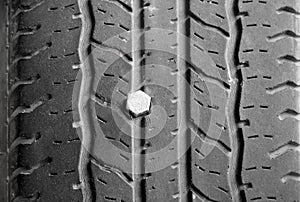Close up of rubber tires leak, automobile tire drilled with a metal screw nail