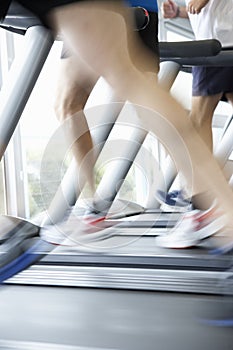 Close Up Of 3 Runners Feet On Running Machine In Gym