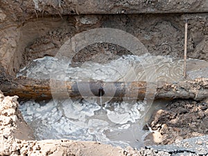 Close-up of ruptured sewer rusty pipeline which cause sewage leakage stream and pollution. old infrastructure issues in the city