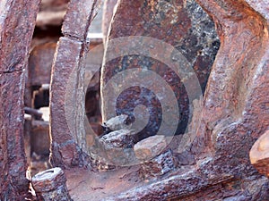 a close up of rusted iron connecting rods and gears with bolts on old corroded machinery