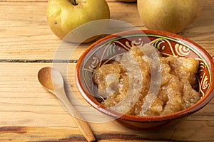 Close-up of rustic bowl with cinnamon applesauce on table with pippin apples and wooden spoon