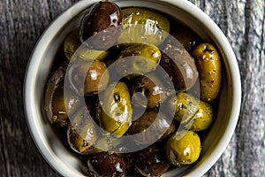Close up of rustic bowl of mixed olives on wood