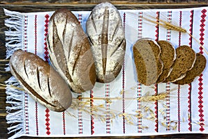 Close-up rustic still life - three loaves and several pieces of wheat-rye bread on a towel.