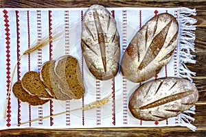 Close-up rustic still life - three loaves and several pieces of wheat-rye bread on a towel.