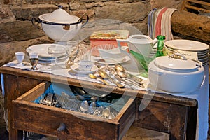 close-up of a rustic table with old kitchenware, glasses, cutlery, plates and tureens in a Catalan farmhouse