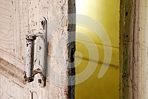 Close-up of the rustic white door handle in the room of abandoned shabby building