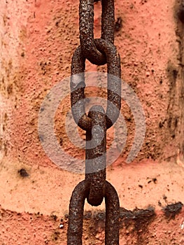 Close-up of a rusty chain in front of red rusty steel drum