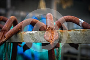 Close up of a rusty grappling hook, hanging on a wooden beam
