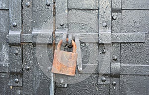 A close up on a rusty padlock on an old, antique black metal door as a symbol of mystery, privacy or secret