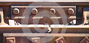 Close up of rusty railway track showing the nuts and bolts of the fishplate which joins sections of track