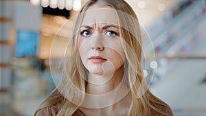 Close-up sad angry serious female face indoors portrait blond 20s girl millennial Caucasian woman lady confused female