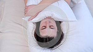 Close up of sad depressed young woman lying on bed at home embraces pillow feels unhappy