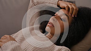 Close up sad despair girl with stress depress lying on couch young African American anxious woman rest on sofa