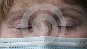 Close Up Of The Sad Eyes Of An Elderly Woman In A Protective Mask On Her Face