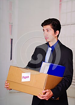 Close up of sad man holding a box after being fired from his job in a blurred background
