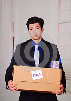 Close up of sad man holding a box after being fired from his job in a blurred background