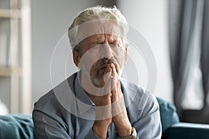 Close up sad mature man praying with hope alone