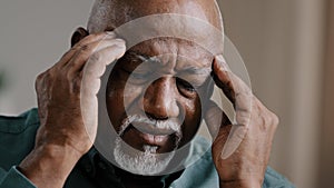 Close-up sad suffering elderly African American old sick ill man feeling headache chronic migraine bad pain unhealthy