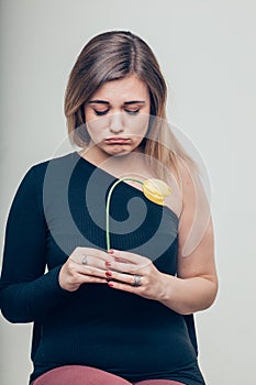 Close up Sad Young Woman Holding a Dead Rose Flower While Looking at the Camera