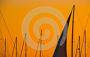 Close up of a sail silhouette under an orange sky at dusk