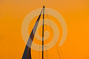 Close up of a sail silhouette under an orange sky at sunset