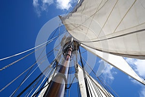 close-up of sailboat mast and rigging, with the sails billowing in the wind