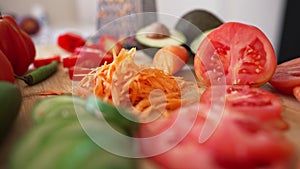 Close-up salad ingredients lying on wooden cutting board on table. Live camera moves forward slowly. Healthful organic