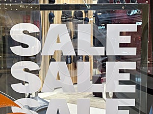 Close-up of a \'SALE\' sign on a shop window with reflections