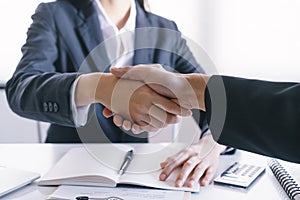 Close-up of salesman shaking hands with lovers who are customers In her office in the house purchase agreement Asian women and men