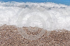 Close up sand beach with bubbles and big blue sea water wave
