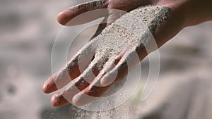 Close-up of sand falling through the fingers