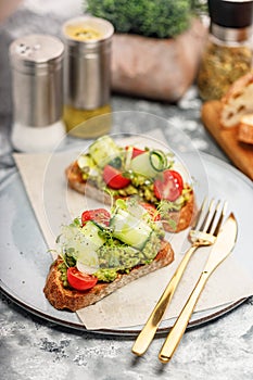 Close-up Sandwiches with guacamole sauce and fresh vegetables on a round plate. Toasts with avocado, cucumber, cherry tomatoes