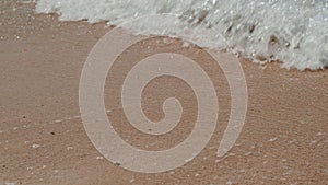 a close up of a sandy beach with waves crashing on it