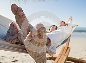 Close up of sandy feet of couple in a hammock