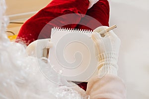 Close-up. Santa Claus writes a letter in a notebook. Place for text