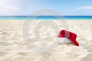 Close up Santa hat on a white sandy infinity caribbean beach . Christmas Holiday Travel Concept