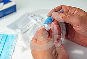 Close up SARS Cov 2 coronavirus rapid antigen test nasal kit. A man doing Covid-19 Self test at home. Hand holding test on white b