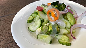 Close up of sauce for pork satay, pickles which are cucumber slices and onions in vinegar, serving on white plate