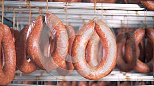 Close up of sausages tied up to a metal crossbar in a factory unit