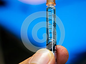Close up scale of tuberculin syringe and blue background of patients unit in hospital.
