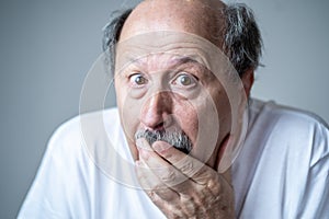 Close up of scared and shocked senior man gesturing in fear with hands and face