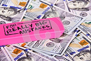 Close up scattered US Dollars with message on pink eraser for really big mistake. Fixing financial, business, taxes problems photo
