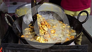 A close-up scene of frying crispy tikadi called flitter and pakoda Indian street food, onion pakora specially for rainy season