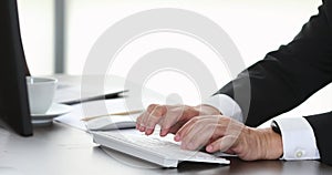 Close up scene video of businessman typing on computer keyboard alone in front of computers in modern office.