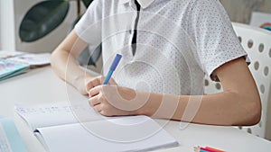 A close-up of a schoolboy's hands with a pen, focused on studying and writing notes