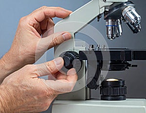 Close-up of Scientist Adjusting Microscope in Laboratory Setting