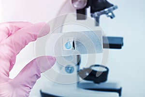 Close-up of scientist in a laboratory microscope with microscope slide in