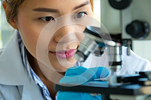 Close up scientist looking through a microscope in a laboratory. Science technology research and development concept