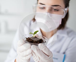 Close up of scientist with plant and soil in lab