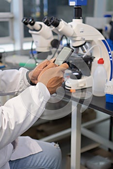 Close-up of a scientist using a cell phone in the laboratory